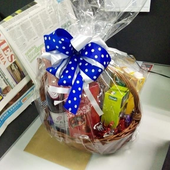 Wicker gift basket with a blue polka-dot bow, wine and treats