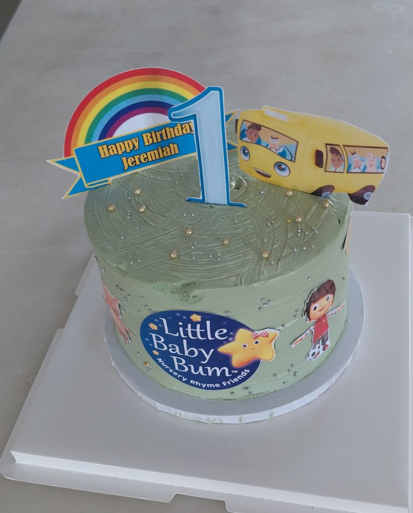 Character birthday cake with a rainbow topper, number one, yellow bus and nursery rhyme characters